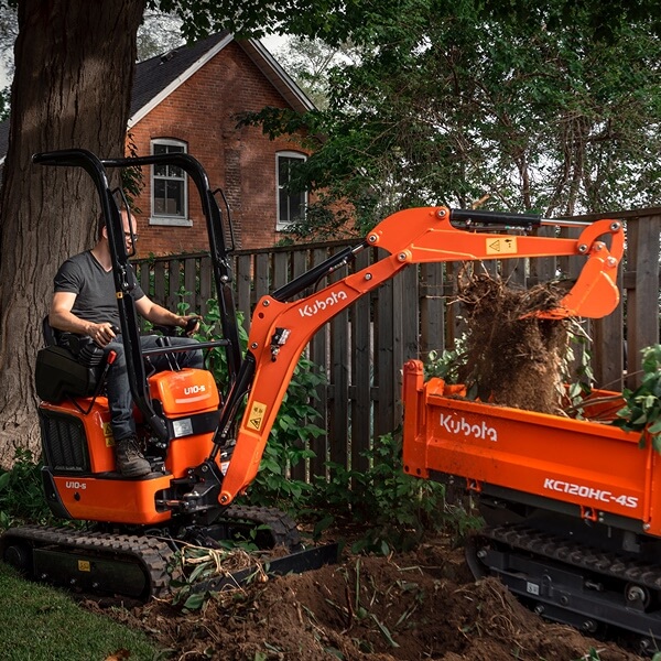 Une mini-pelle orange Kubota en action sur un terrain en terre, démontrant sa puissance et sa précision pour des travaux de terrassement ou de paysagisme.