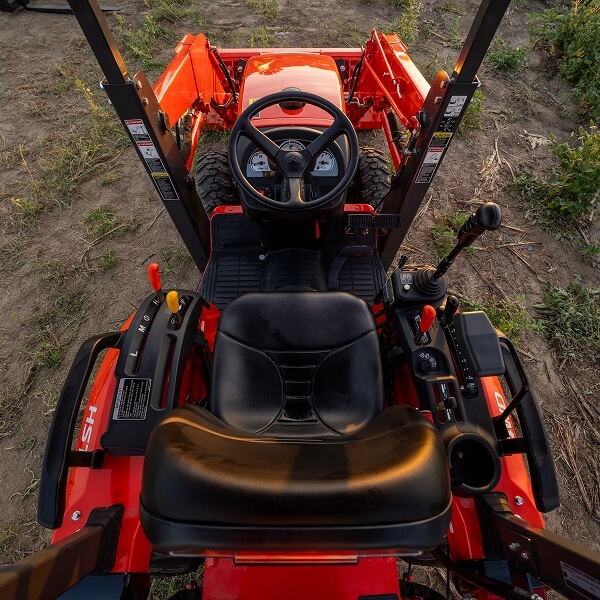 Tracteur orange avec un siège conducteur et un volant, prêt à être utilisé dans les champs.